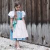Schnittmuster Kinderdirndl Resli für Mädchen in Gr. 80-140 von TOSCAminni. Das Bild zeigt das fertig genähte Trachtendirndl mit passender Schürze und Mieder. Professionelle PDF-Nähanleitung für traditionelle Kindertrachten.